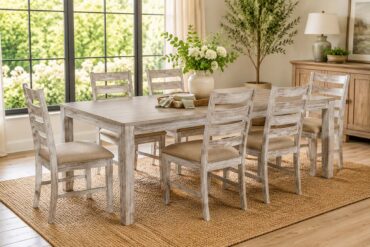 Six-piece distressed wood dining set with ladder-back chairs arranged around a rectangular dining table in a bright farmhouse-style dining room, featuring large black-framed windows, natural light, neutral decor, and a woven jute rug.