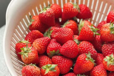 A vibrant collection of fresh strawberries in a white colander,