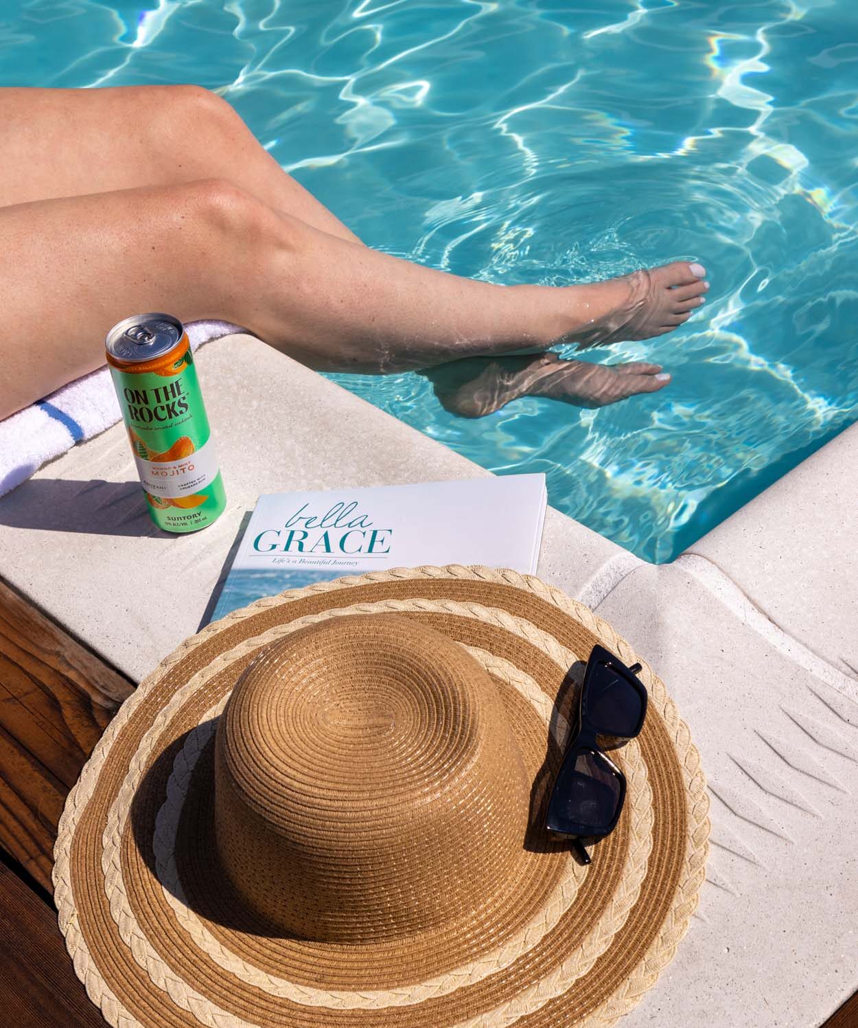 Guest relaxing poolside at the rooftop pool at Merriweather Lakehouse Hotel in Columbia Maryland with feet dangling in the bright turquoise water on a sunny summer day