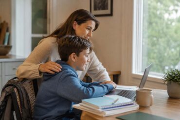 Parent and child looking at a laptop together during a home-based online school session, illustrating mid-year enrollment support