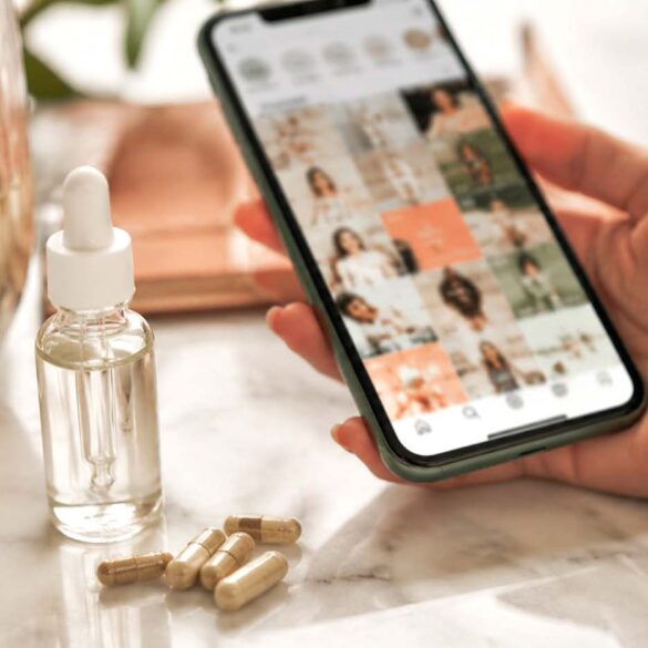 Hand holding phone scrolling wellness content next to peptide supplement vials, illustrating the peptides trend