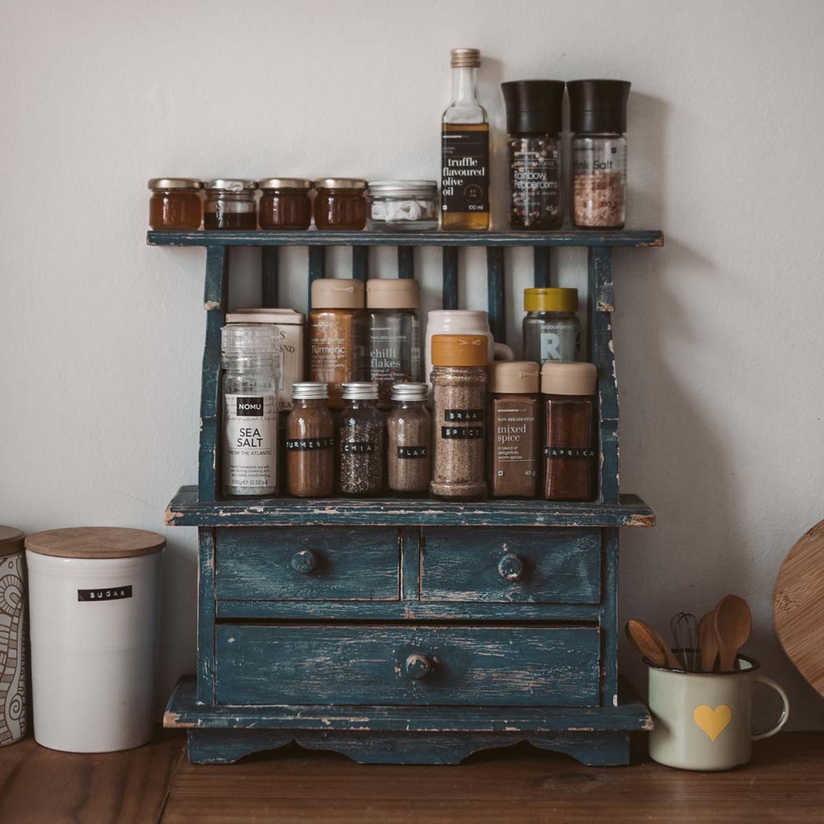A charming rustic spice rack with various glass jars and wooden containers in a cozy kitchen setting.