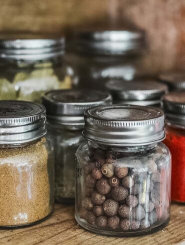 Close-up of assorted spice jars with various herbs on a kitchen shelf, showcasing colorful culinary ingredients