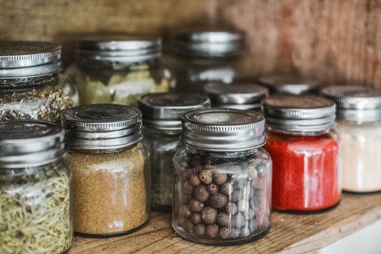 Close-up of assorted spice jars with various herbs on a kitchen shelf, showcasing colorful culinary ingredients