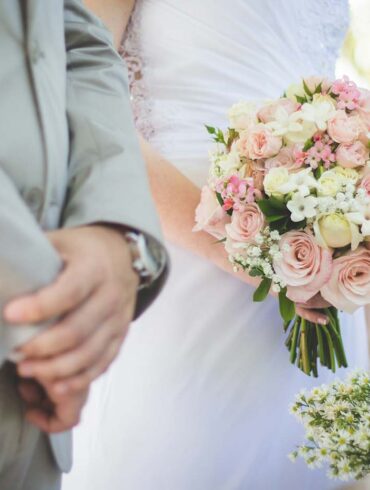 a couple at the alter getting married. up close shot of their hands and bouquet.