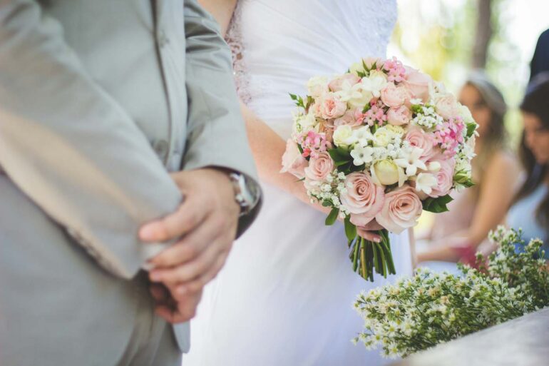 a couple at the alter getting married. up close shot of their hands and bouquet.