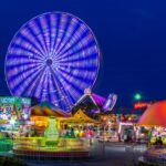 Colorful Ferris wheel and theme park at night creating a vivid and energetic scene.