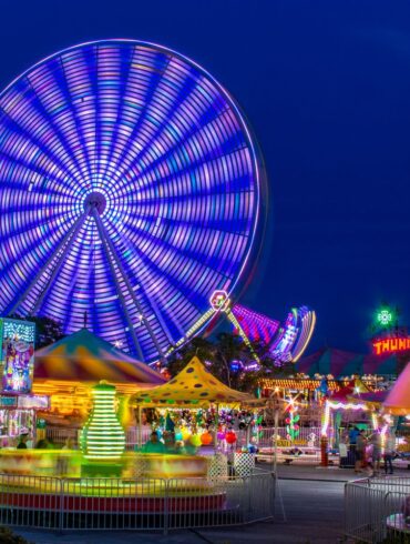 Colorful Ferris wheel and theme park at night creating a vivid and energetic scene.