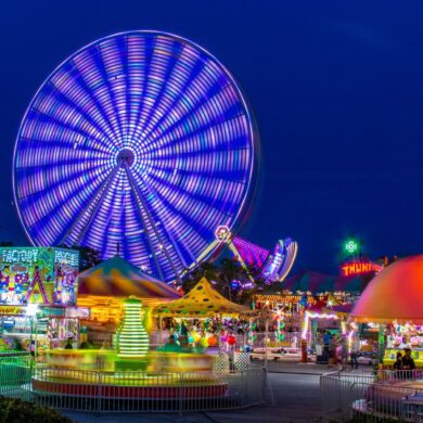 Colorful Ferris wheel and theme park at night creating a vivid and energetic scene.