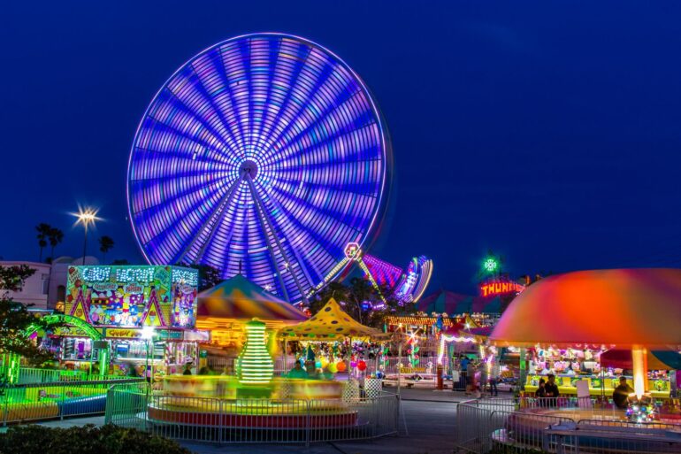 Colorful Ferris wheel and theme park at night creating a vivid and energetic scene.