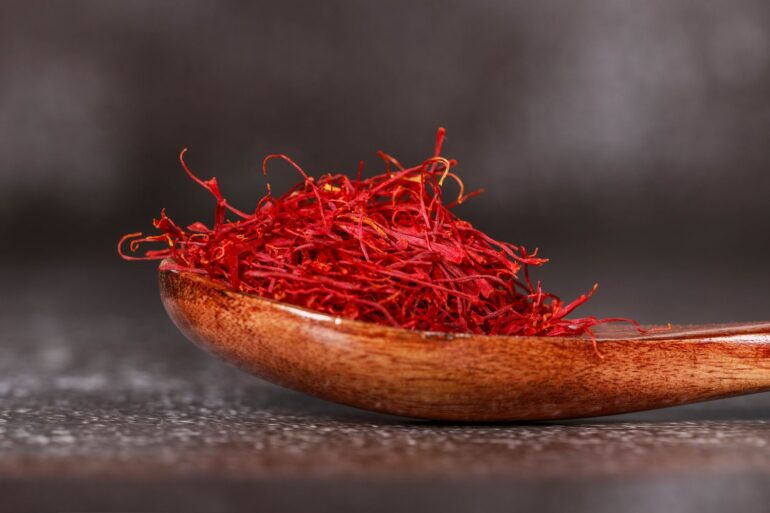 Detailed close-up of vibrant saffron threads in a wooden spoon