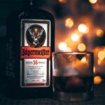 A glass and bottle of Jagermeister on a bar with dramatic lighting.