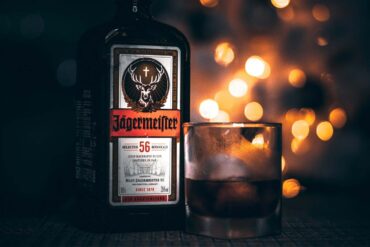 A glass and bottle of Jagermeister on a bar with dramatic lighting.