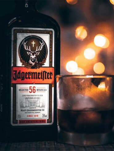 A glass and bottle of Jagermeister on a bar with dramatic lighting.