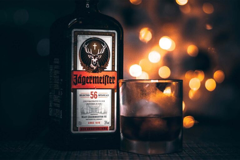 A glass and bottle of Jagermeister on a bar with dramatic lighting.