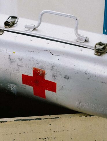 an old metal first aid kit in storage, possibly filled with expired items
