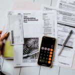 person doing their year end taxes holding paper near pen and calculator