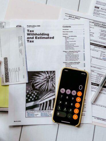 person doing their year end taxes holding paper near pen and calculator