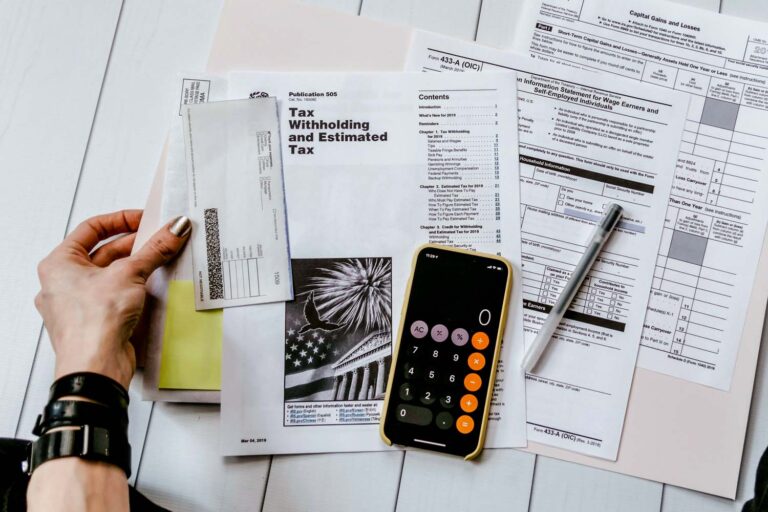 person doing their year end taxes holding paper near pen and calculator