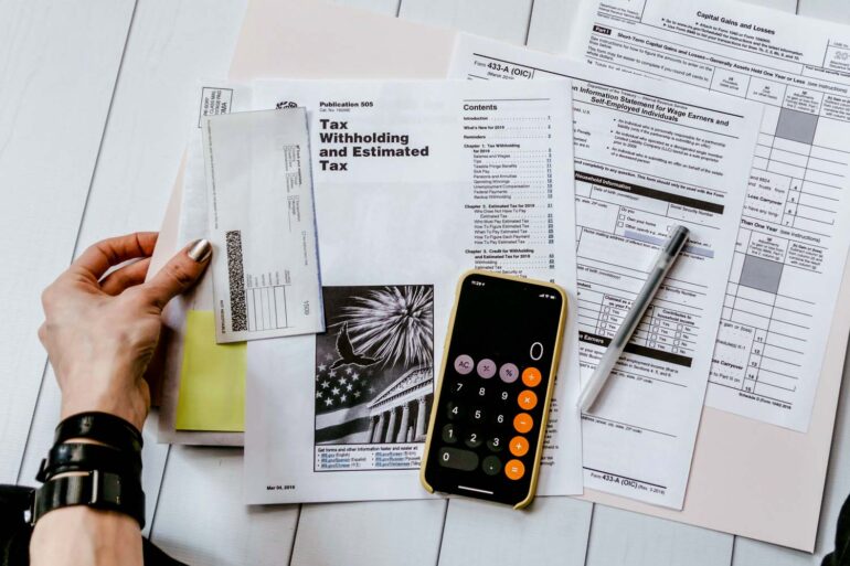 person doing their year end taxes holding paper near pen and calculator