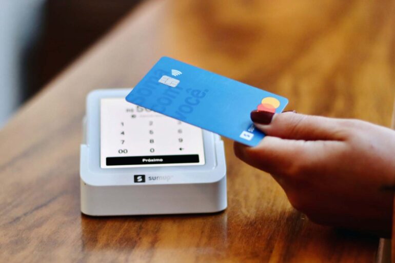 a person holding a credit card in front of a machine