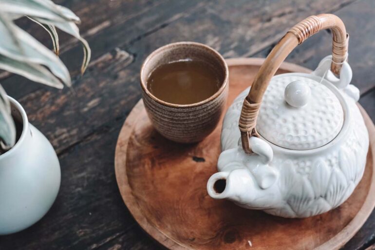 white and brown ceramic teapot on wooden tray