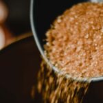 Close-up of brown sugar being poured into a dark ceramic bowl, creating a sweet and rustic feel