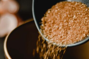 Close-up of brown sugar being poured into a dark ceramic bowl, creating a sweet and rustic feel
