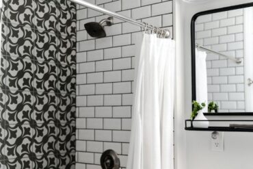 a modern titled bathroom with the shower curtain left open