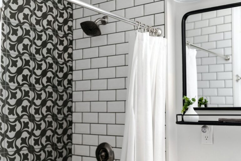 a modern titled bathroom with the shower curtain left open