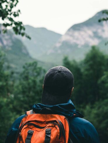 A man hiking in a blue and orange hoodie wearing black knit cap and backpack at Grands-Jardins National Park, Québec, Canada