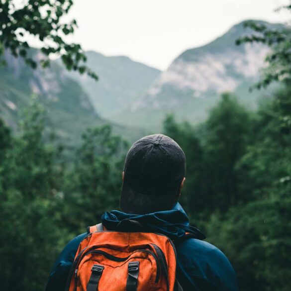 A man hiking in a blue and orange hoodie wearing black knit cap and backpack at Grands-Jardins National Park, Québec, Canada