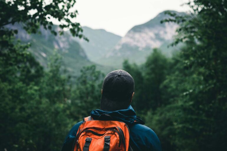 A man hiking in a blue and orange hoodie wearing black knit cap and backpack at Grands-Jardins National Park, Québec, Canada