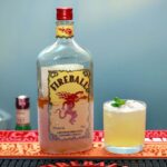 a bottle of fireball on a bar next to a cocktail