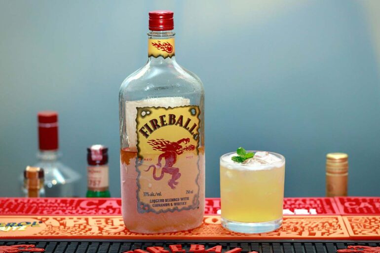 a bottle of fireball on a bar next to a cocktail