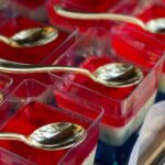 Close-up of colorful layered jello desserts with spoons on a tray