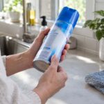a person looking for expiration dates on the side of a can of Lysol
