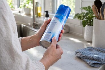 a person looking for expiration dates on the side of a can of Lysol