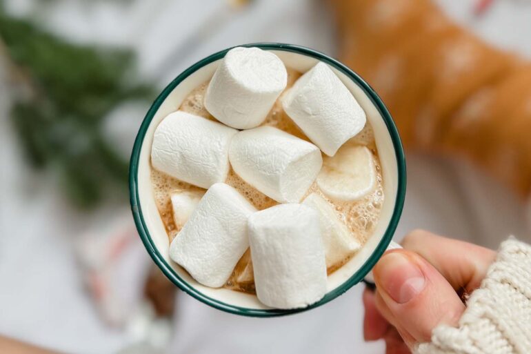 Close-up of several large marshmallows in a mug of hot chocolate evoking a cozy winter vibe.