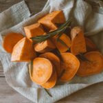 a sliced sweet potato prepped on a rustic table