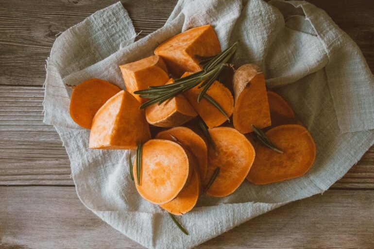 a sliced sweet potato prepped on a rustic table