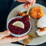 a gourmet meal featuring cranberry sauce with lemon slice, turkey, and mashed sweet potatoes.