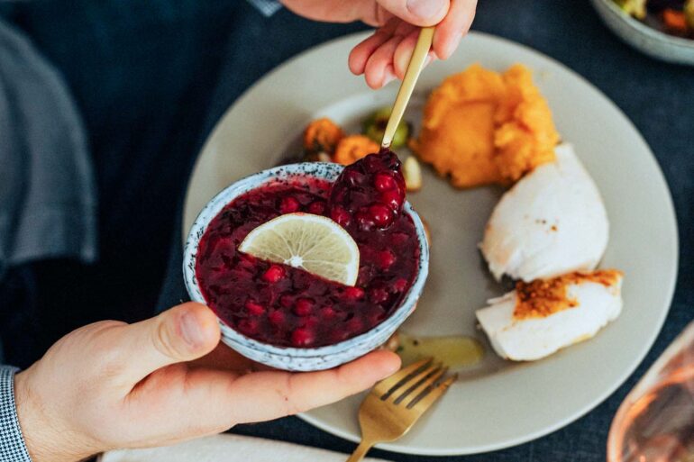 a gourmet meal featuring cranberry sauce with lemon slice, turkey, and mashed sweet potatoes.