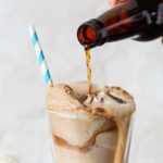a close up bottle of root beer being poured into an ice cream float
