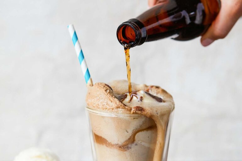 a close up bottle of root beer being poured into an ice cream float