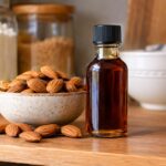 a bottle of almond extract on a kitchen counter next to a bowl of almonds