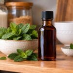 a bottle of peppermint extract on a kitchen counter next to a bowl of mint leaves
