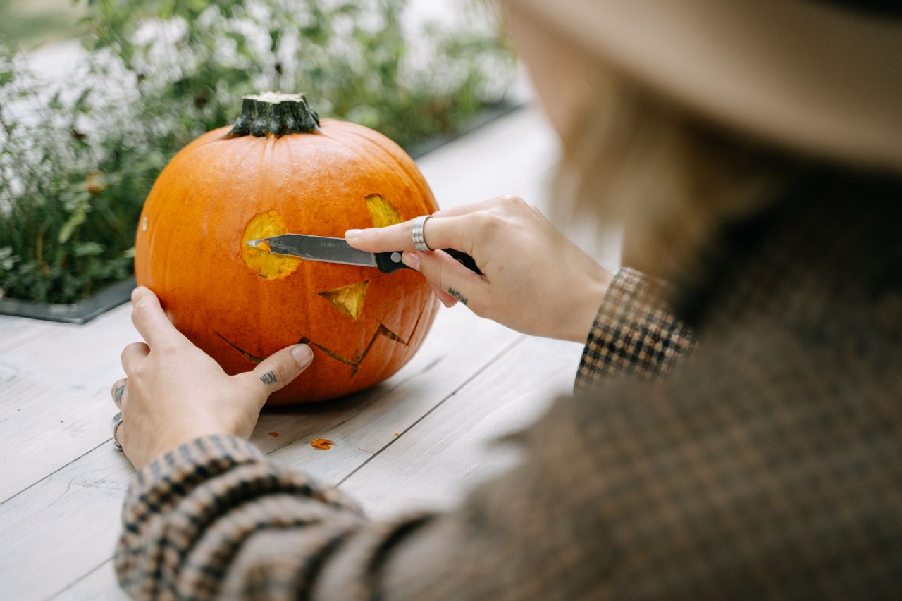 a woman carving a jack o lantern on a table