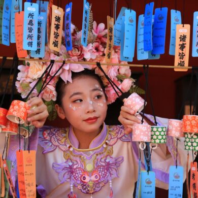 A young Asian woman in traditional attire surrounded by vibrant lanterns and wishes, capturing cultural celebration.