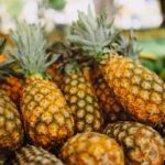 A store display of ripe pineapples stacked in a produce section